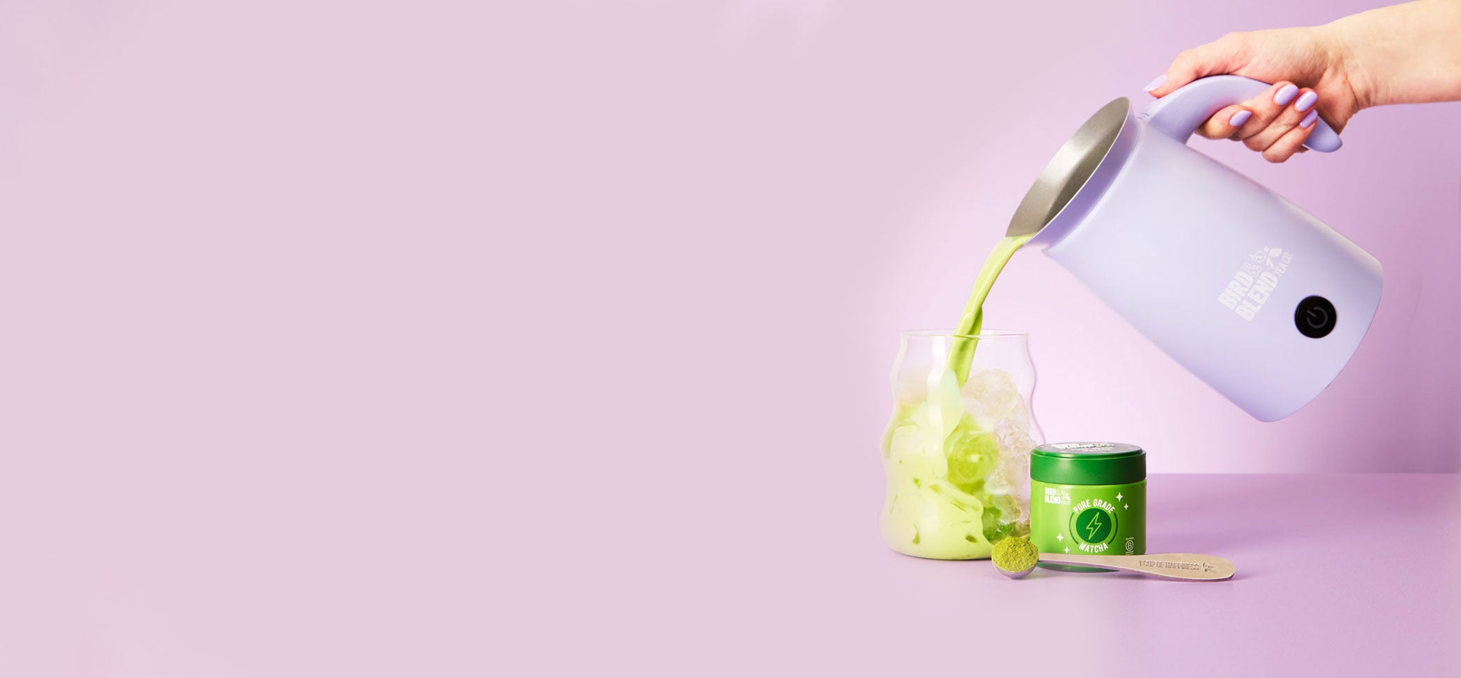 soft lilac magic whisk pouring pure grade matcha into iced matcha & pure grade tin & perfect matcha spoon filled with pure grade matcha powder