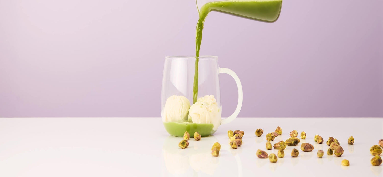 Pistachio Gelato Matcha Tea pouring onto vanilla ice cream in a mug with pistachios 