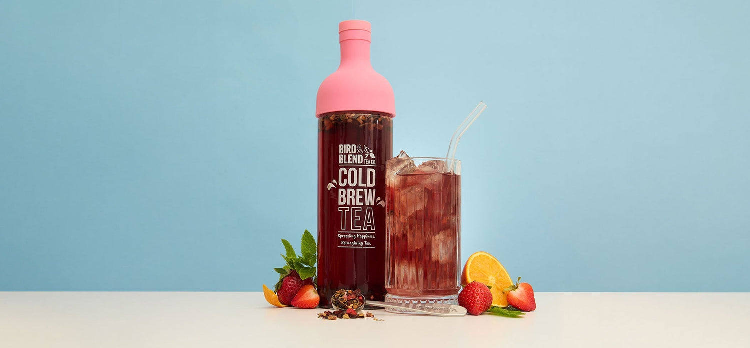 Summer in the garden cold brew tea in peachy pink cold brew tea bottle and iced tea in cup and spoon filled with loose leaf tea