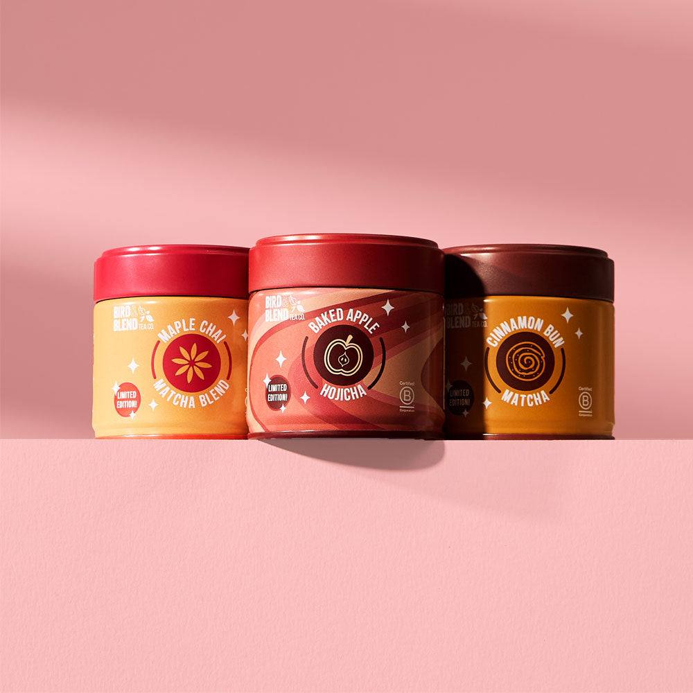  cinnamon bun matcha tin & baked apple hojicha tin & maple chai matcha blend tin on a pink table 