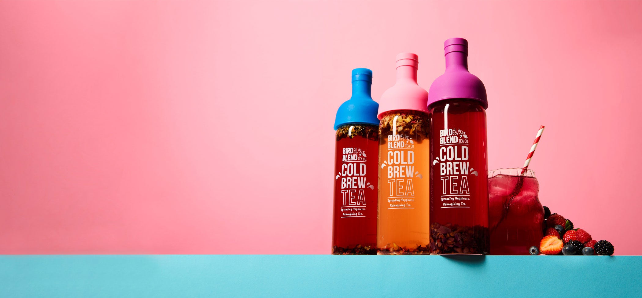 peachy pink plum purple & sapphire blue cold brew tea bottle filled with tea next to iced tea