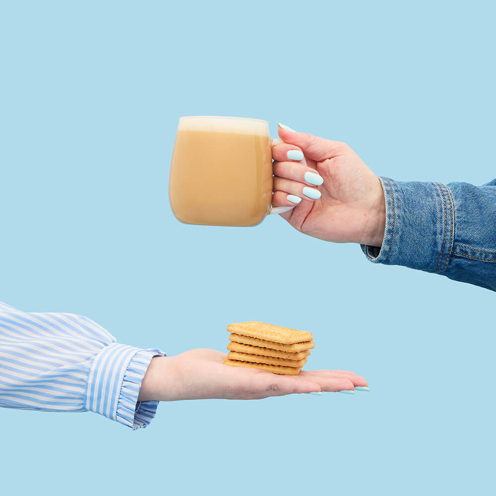 hand holding malted milk biscuit &amp; malted milk hot tea latte in mug