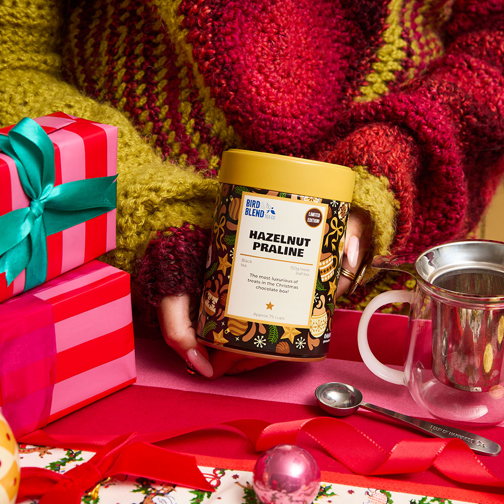 person holding hazelnut praline tea tin 