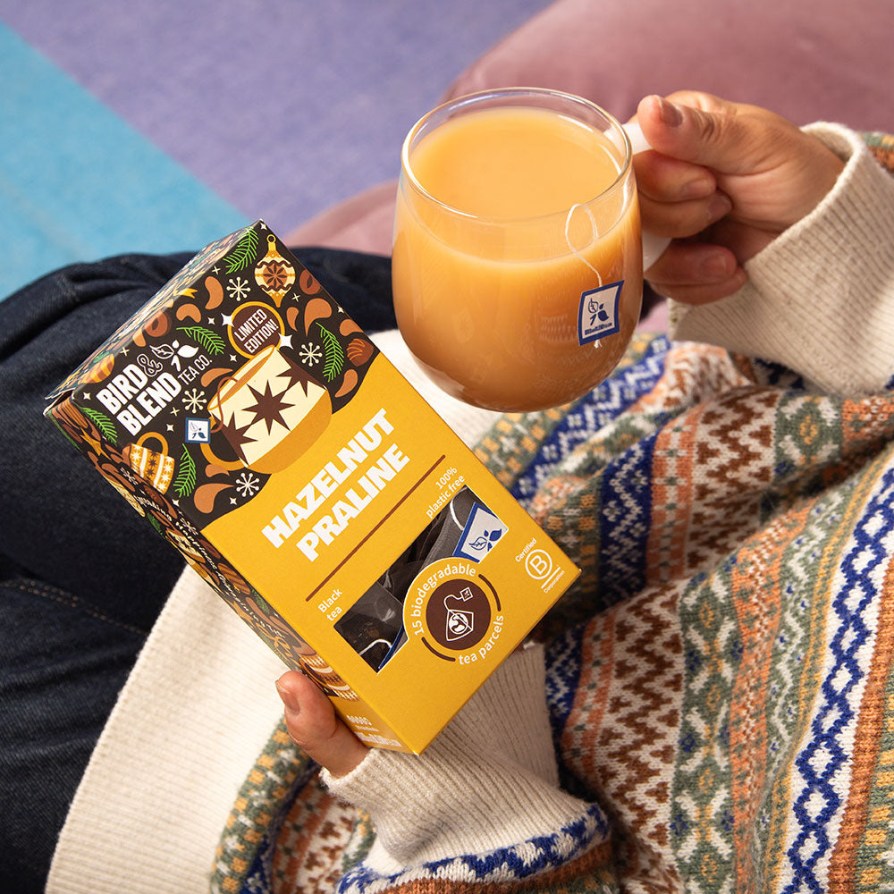 person holding hazelnut praline tea 150g gift tea bag and hot tea