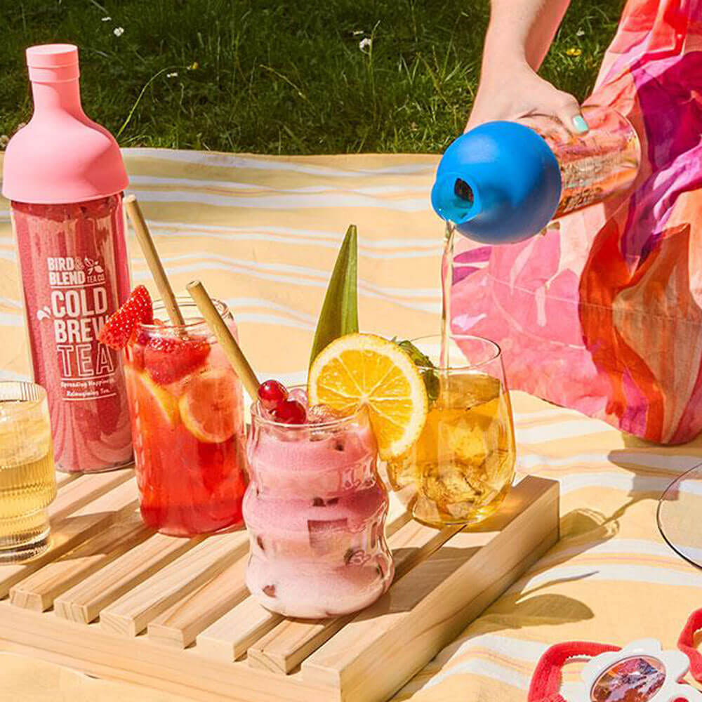sapphire blue cold brew tea bottle pouring iced cold brew tea and peachy pink cold brew tea bottle with fruit iced iced