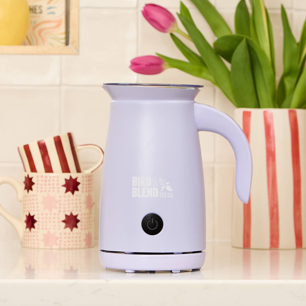 soft lilac matcha latte magic whisk with mugs and vase of flowers in the background